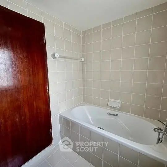 Spacious bathroom with tiled walls and built-in bathtub, perfect for relaxation.