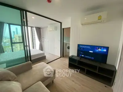 Modern condo living room with TV, sofa, and glass partition to bedroom, featuring city view.