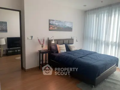 Spacious bedroom with modern decor and natural light in a stylish apartment.