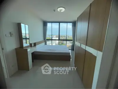 Spacious bedroom with large windows offering stunning city views in modern apartment.