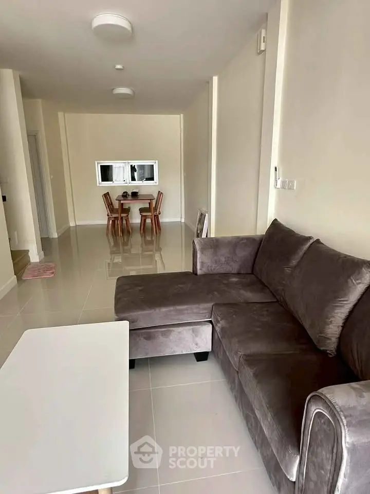 Spacious living room with plush gray sofa and modern dining area, perfect for relaxation and entertaining.