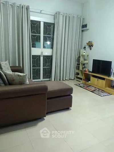 Cozy living room with modern sofa and entertainment center, featuring elegant curtains and sleek flooring.