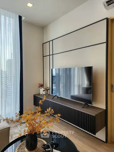 Modern living room with sleek TV setup and stylish decor in a high-rise apartment.