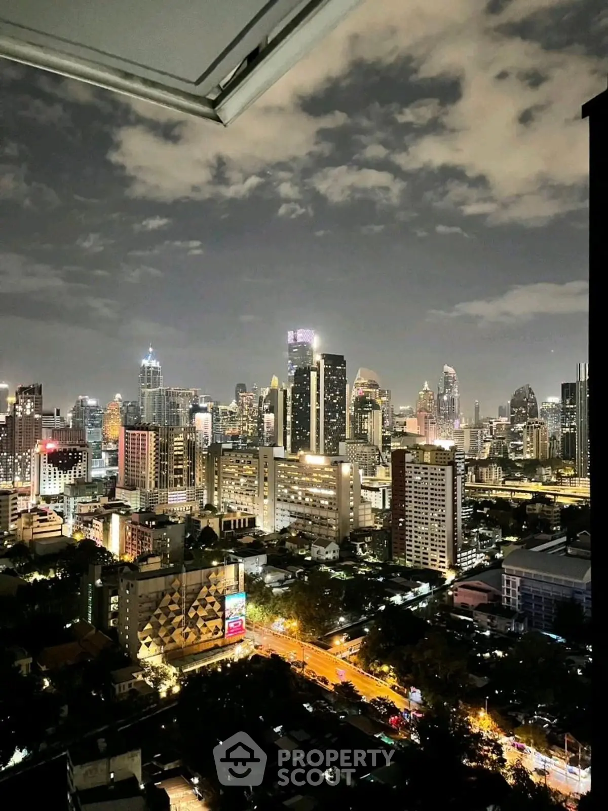 Stunning city skyline view from high-rise balcony at night, showcasing vibrant urban lights.