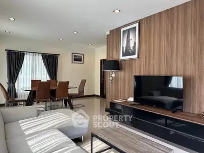 Modern living room with stylish decor and dining area, featuring a sleek TV setup.