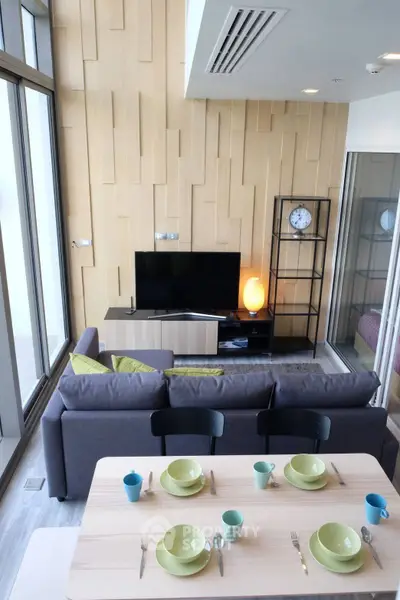 Modern living room with stylish decor and open layout, featuring a cozy sofa and dining area.