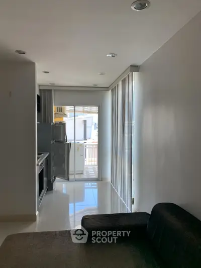 Modern apartment interior with sleek kitchen and cozy living area, featuring large windows for natural light.