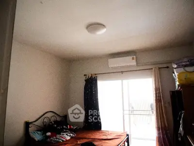 Cozy bedroom with natural light and balcony access, featuring a comfortable bed and air conditioning.