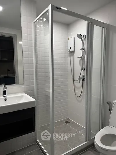 Modern bathroom with glass shower enclosure and sleek fixtures in a contemporary apartment.