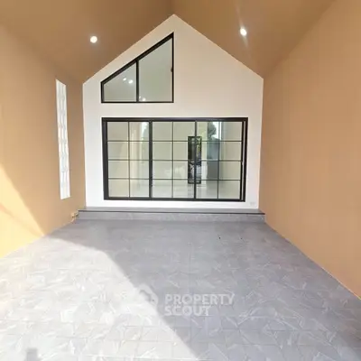 Spacious modern room with high ceiling and large windows, perfect for natural light.