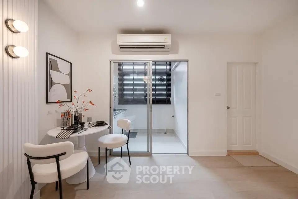 Modern dining area with stylish decor and sliding glass doors leading to a bright room.
