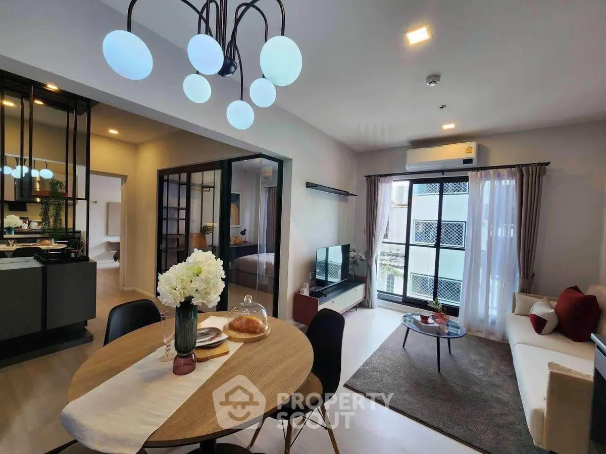 Modern open-plan living room with stylish decor and dining area, featuring large windows and elegant lighting.