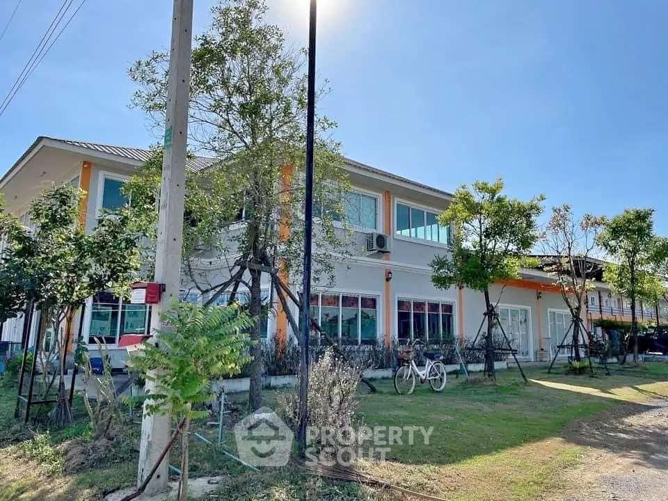 Charming two-story building with lush greenery and ample natural light, perfect for residential or commercial use.