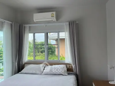 Bright and airy bedroom with large windows and air conditioning, offering a serene view of lush greenery.