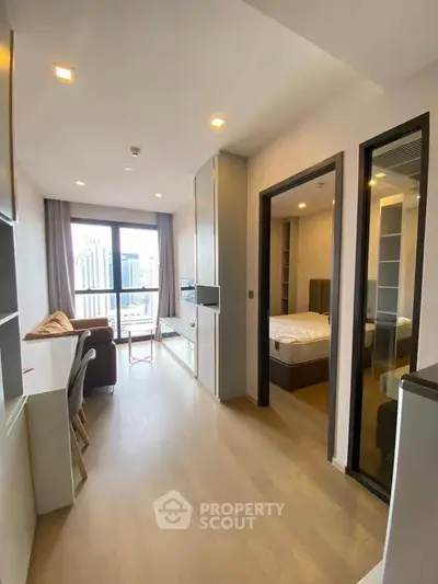 Modern apartment with open living area and bedroom, featuring city view.