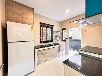 Modern kitchen with sleek design, featuring a refrigerator, washing machine, and ample counter space.