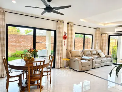 Spacious living room with elegant furniture and large windows offering garden views.