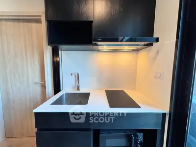 Modern compact kitchen with sleek black cabinetry and built-in appliances