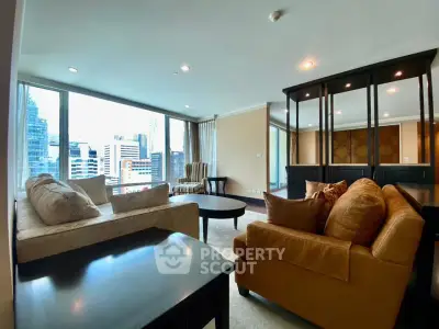 Spacious living room with city view, featuring elegant furniture and large windows.