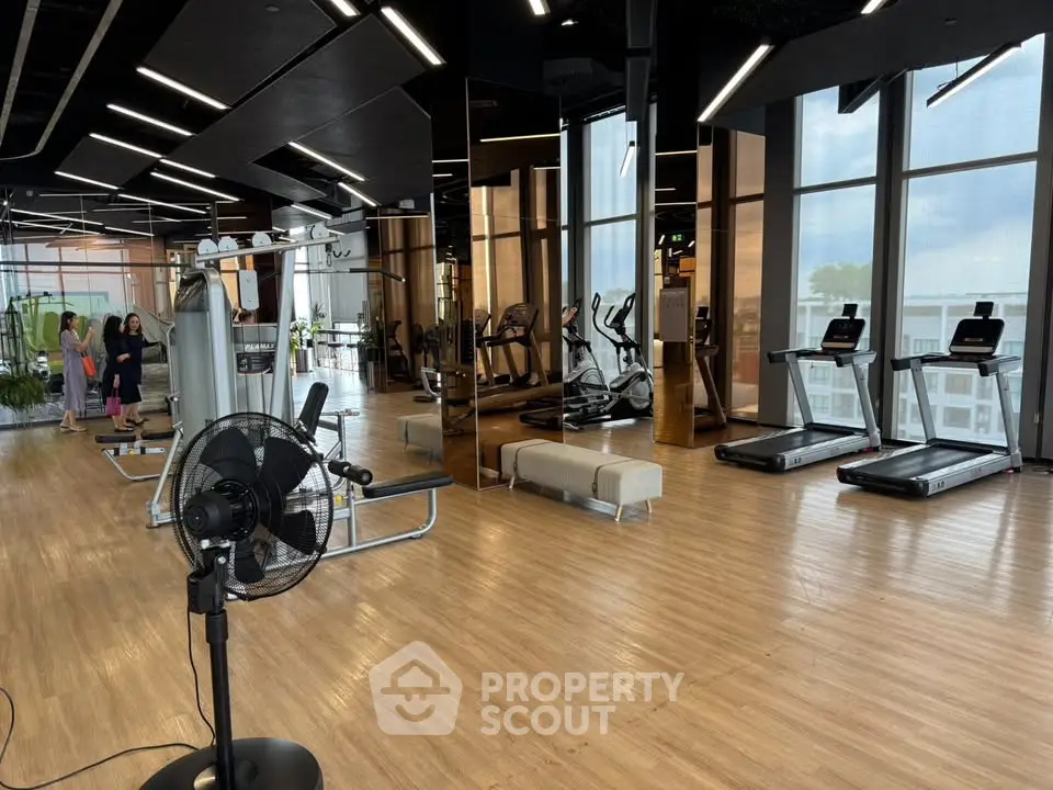 Spacious modern gym with state-of-the-art equipment and large windows offering city views.