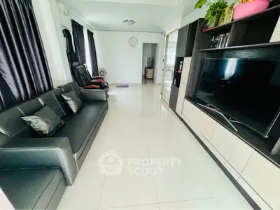 Spacious living room with modern black sofa and large TV unit