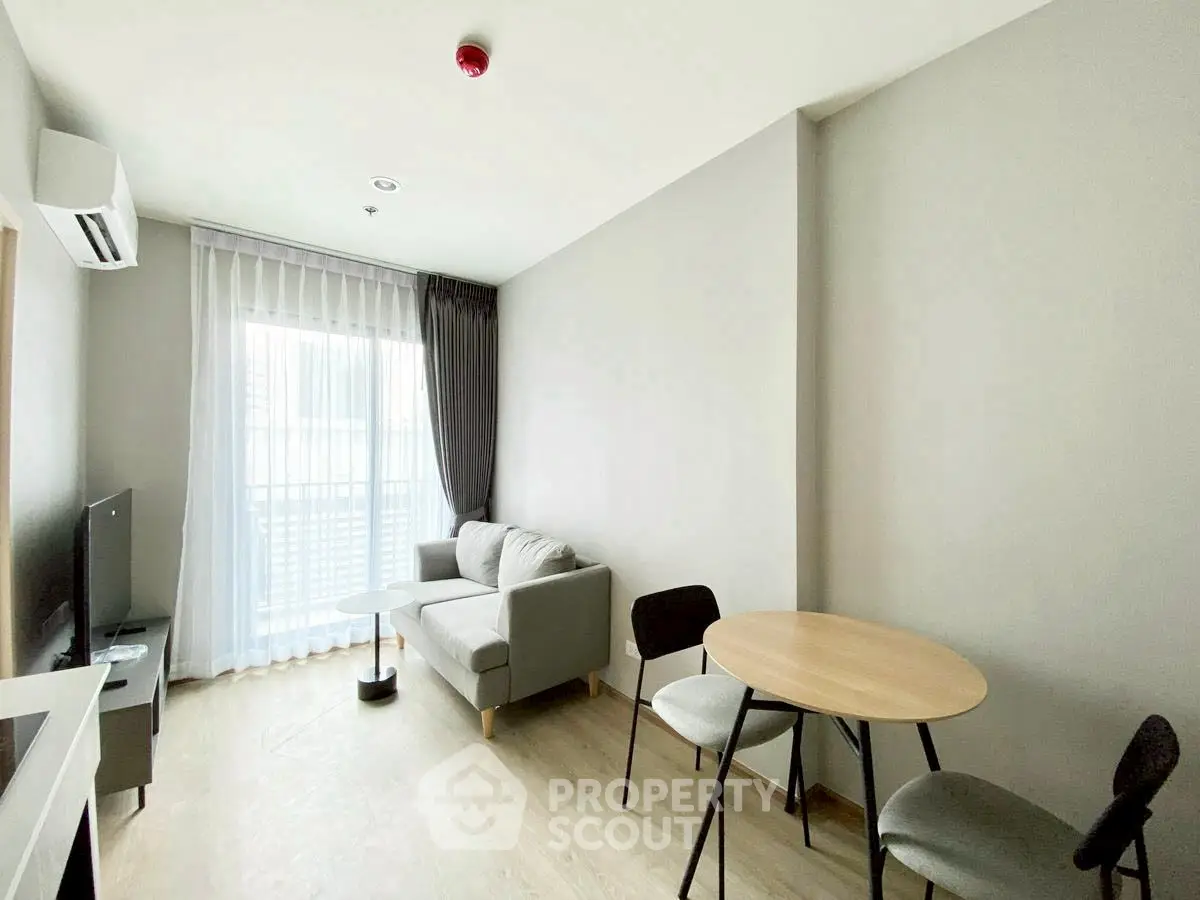 Modern living room with sofa, TV, and dining table in bright apartment