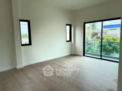 Spacious modern living room with large windows and balcony access, featuring elegant wood flooring.