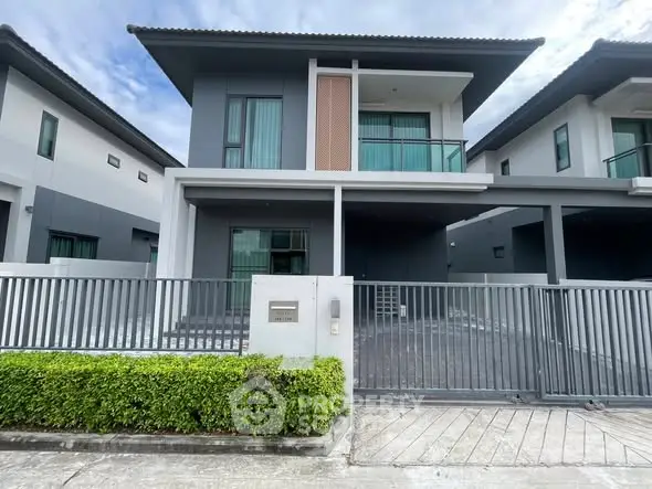 Modern two-story house with sleek design and gated driveway in a suburban neighborhood.