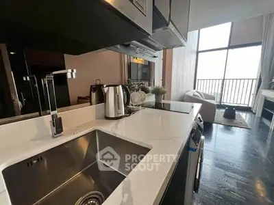 Modern kitchen with sleek appliances and open layout leading to a bright living area.