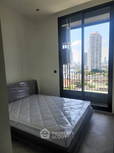 Modern bedroom with city view and large window in high-rise apartment