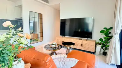 Stylish modern living room with large TV, leather sofa, and elegant decor in a bright apartment.