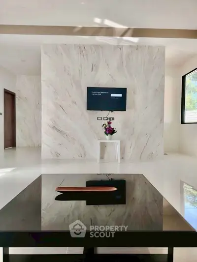 Modern living room with marble accent wall and mounted TV, featuring sleek furniture and natural light.