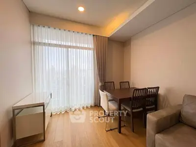 Modern dining area with wooden table and chairs, large window with sheer curtains, and cozy ambiance.
