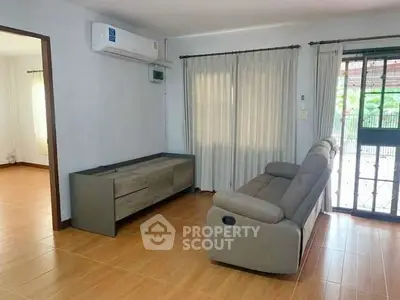 Spacious living room with modern sofa and air conditioning, featuring large windows for natural light.