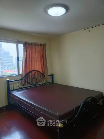 Spacious bedroom with city view and elegant bed frame in modern apartment.