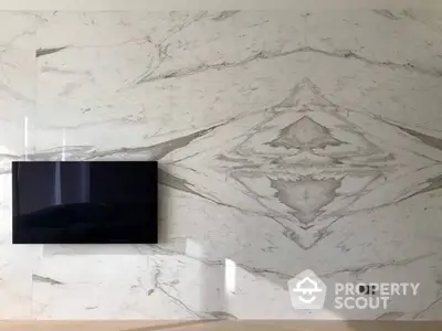 Elegant living room with a wall-mounted flat-screen TV and luxurious marble wall design, perfect for upscale urban living.