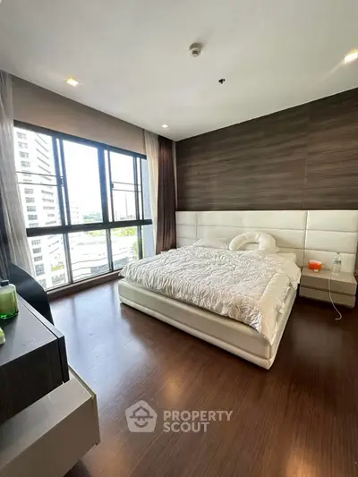 Luxurious bedroom with large windows and modern decor in a high-rise apartment.