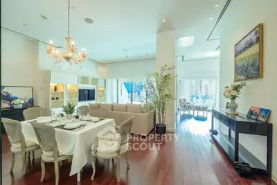 Luxurious open-plan living and dining area with elegant chandelier and city view balcony.
