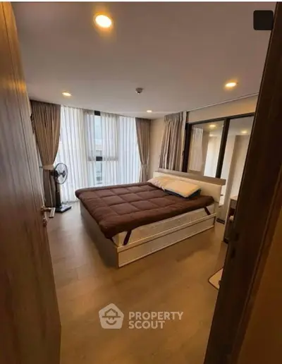 Spacious bedroom with modern decor and large windows in a luxury apartment.