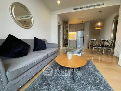 Modern living room with stylish decor and open dining area, featuring a cozy gray sofa and elegant lighting.