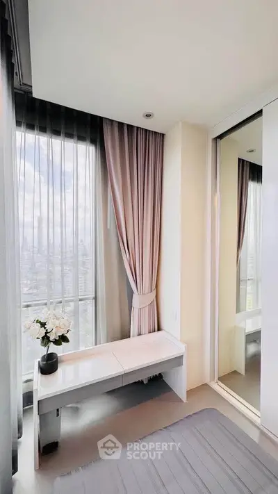 Bright bedroom with large windows and elegant curtains offering a stunning city view.