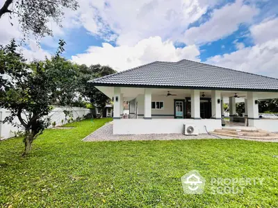 Charming single-story home with spacious lawn and modern roof design under a clear blue sky.