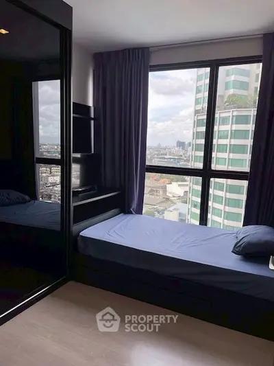 Modern bedroom with city view and sleek furnishings in high-rise apartment.
