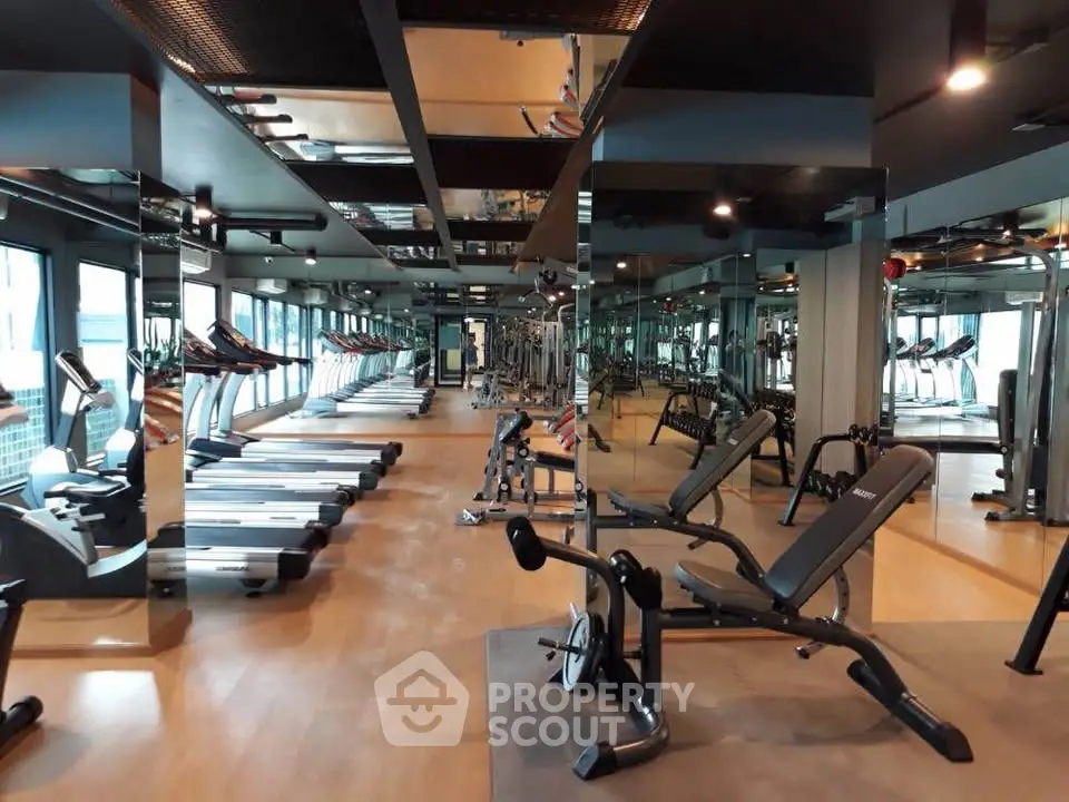 Spacious modern gym with state-of-the-art equipment and mirrored walls in luxury building.