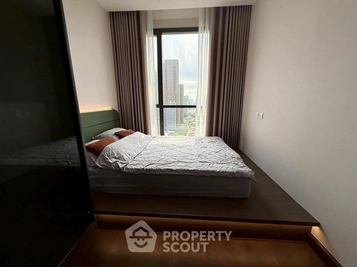 Modern bedroom with city view, featuring a platform bed and floor-to-ceiling window.