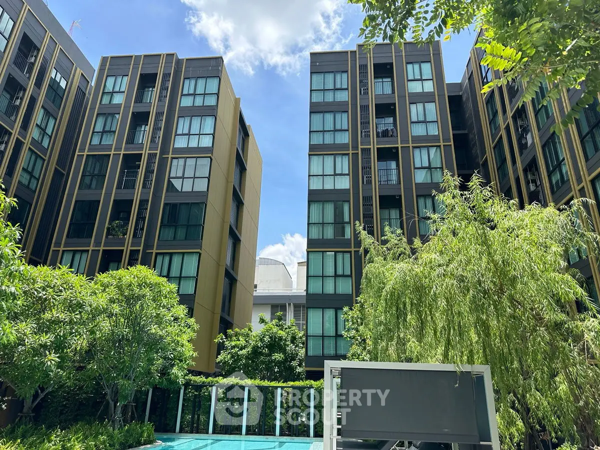 Modern apartment buildings with lush greenery and a clear blue sky, showcasing urban living at its finest.