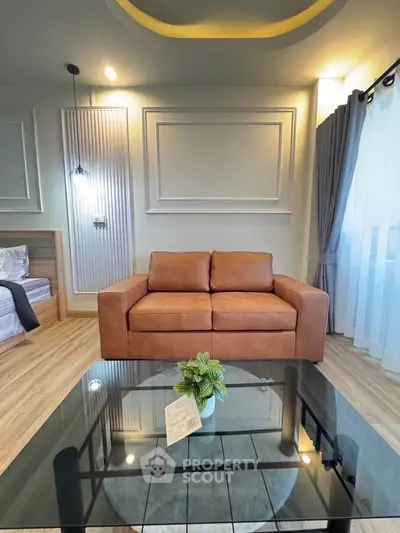 Modern living room with stylish decor and cozy leather sofa, featuring elegant lighting and a glass coffee table.