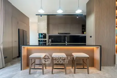 Modern kitchen with sleek design, featuring an island and stylish lighting.