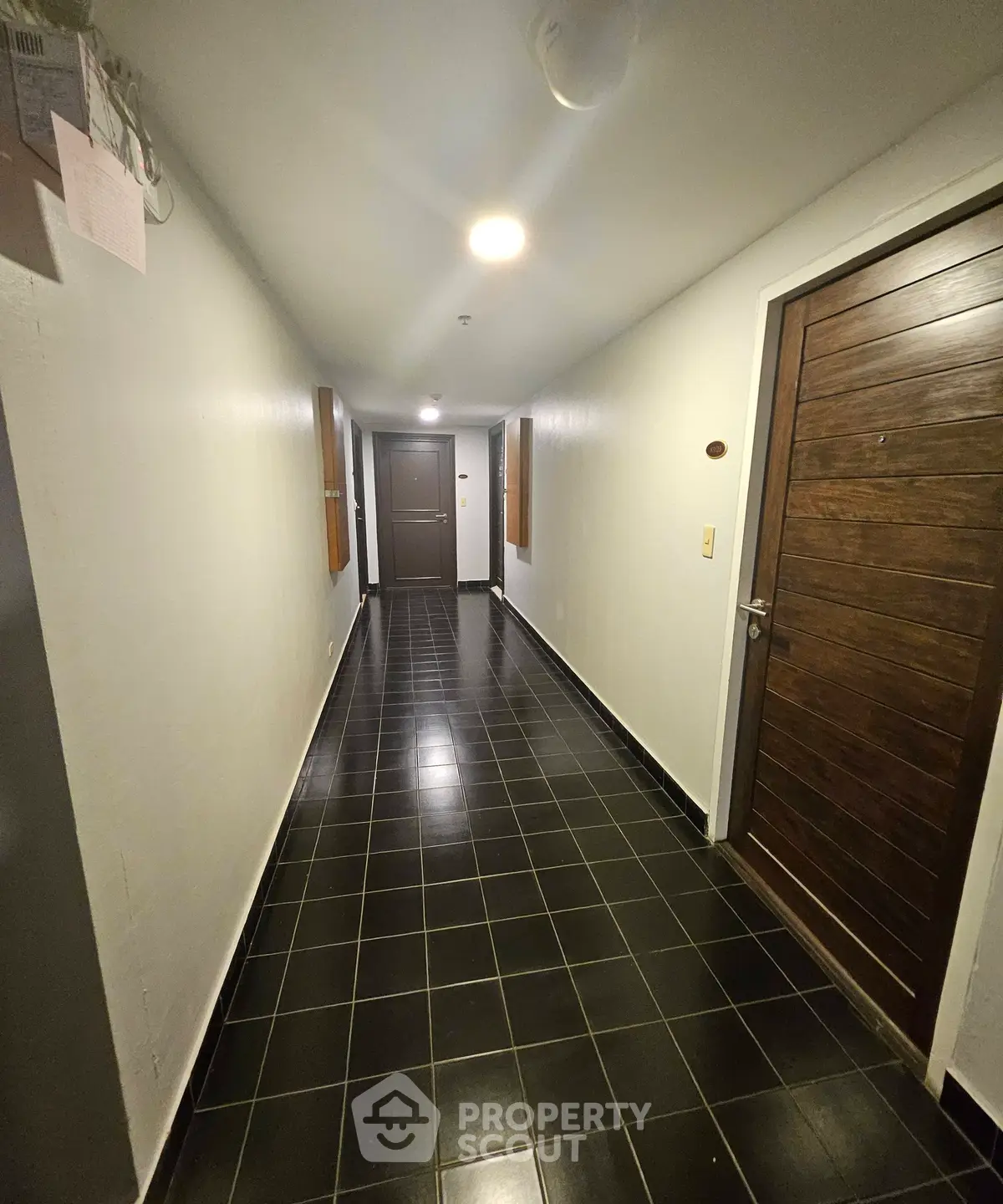Modern apartment hallway with sleek black tiles and wooden doors