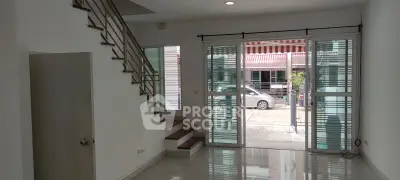 Spacious modern living room with large windows and staircase, offering natural light and street view.
